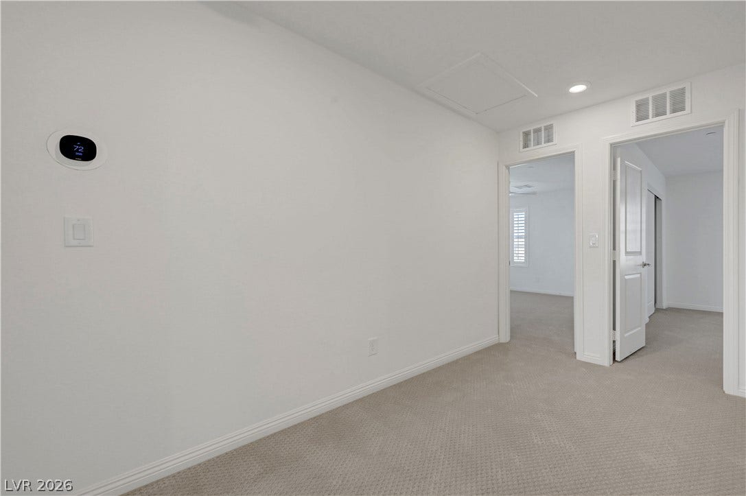 A quiet landing area with plush carpeting connects various rooms, featuring clean white walls and functional ceiling vents.