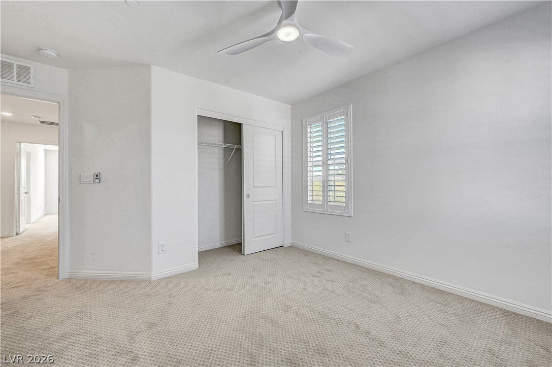 A well-lit bedroom features plush carpet and an open closet for ample storage.
