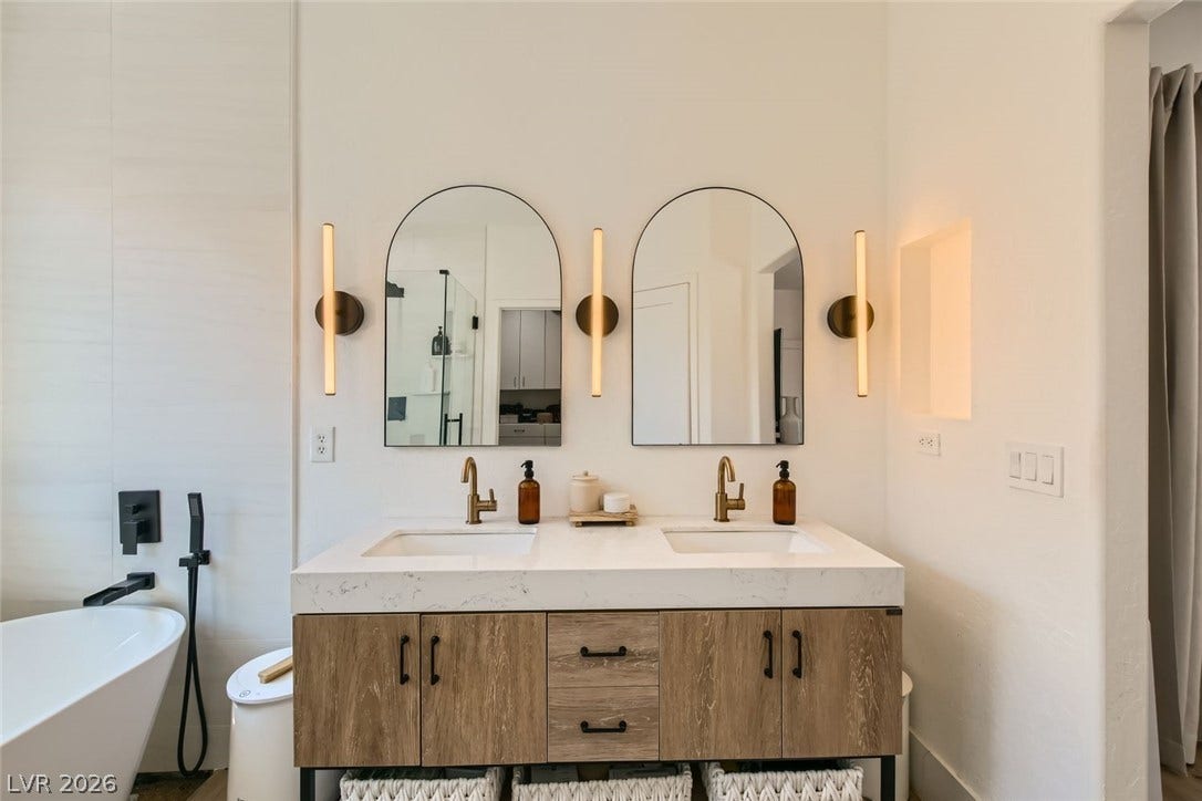 2724 Mintlaw Avenue, Henderson, NV 89044 A well-appointed primary bath features a dual vanity, sleek mirrors, and contemporary lighting.