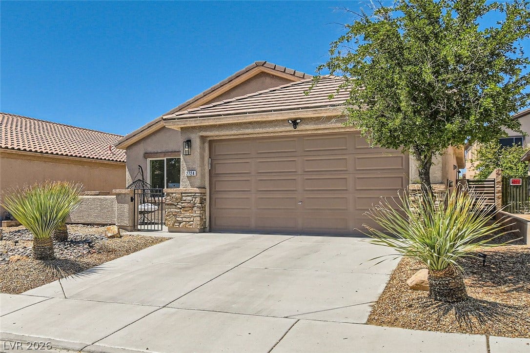 2724 Mintlaw Avenue, Henderson, NV 89044 A well-maintained concrete driveway leads to a welcoming home featuring a stone facade and desert landscaping.