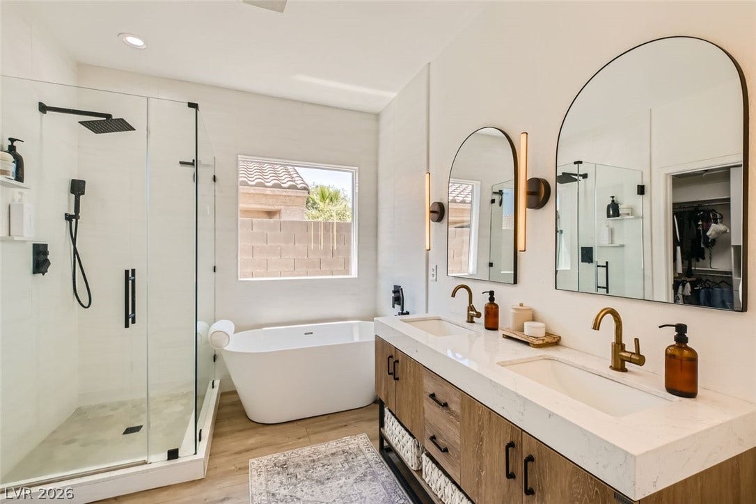 2724 Mintlaw Avenue, Henderson, NV 89044 A well-appointed bath features a spacious glass-enclosed shower, freestanding tub, and a vanity with dual sinks.