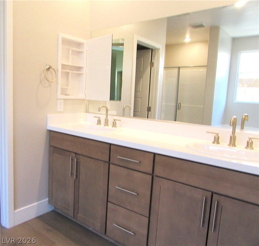 988 Gentle Swan, Henderson, NV 89011 Double vanities with sleek cabinetry and a generously sized mirror elevate this well-appointed primary bathroom. Photo is of actual home.