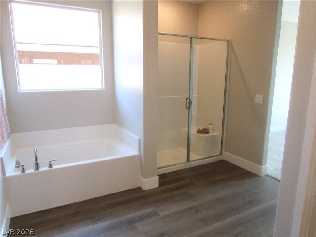 988 Gentle Swan, Henderson, NV 89011 Indulge in a tranquil bathing experience with a generously sized tub and a modern glass-enclosed shower. Photo is of actual home.