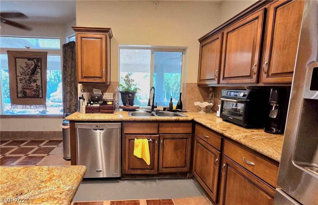 884 E Robindale Road, Las Vegas, NV 89123 A well-appointed kitchen showcasing elegant wooden cabinetry and golden granite countertops.
