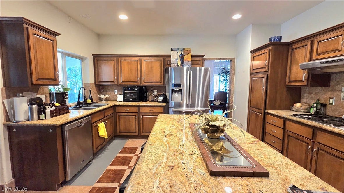 884 E Robindale Road, Las Vegas, NV 89123 An inviting kitchen features a large granite island and ample wood cabinetry for effortless entertaining.