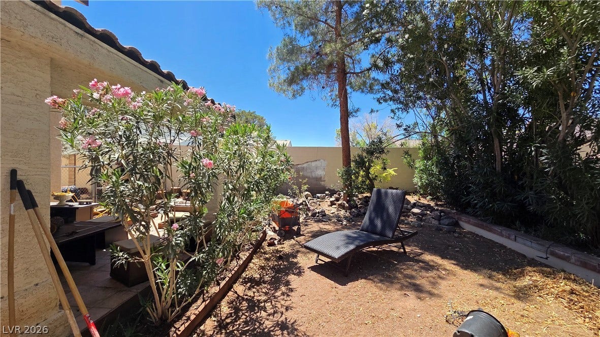 884 E Robindale Road, Las Vegas, NV 89123 A tranquil desert landscape featuring a shaded patio and blooming shrubs.