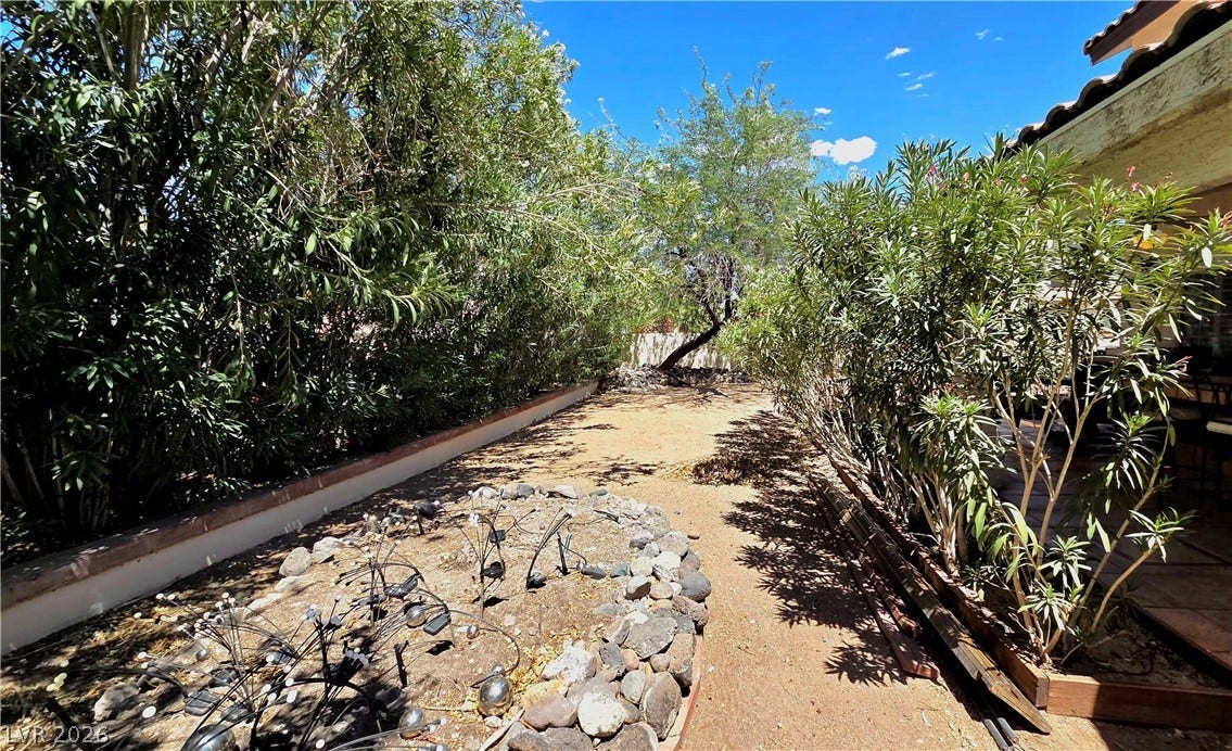 884 E Robindale Road, Las Vegas, NV 89123 An inviting private yard with lush hedges creates a serene outdoor retreat.
