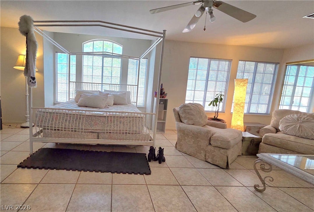 884 E Robindale Road, Las Vegas, NV 89123 Natural light floods this spacious bedroom, featuring a large window and tiled flooring for easy maintenance.