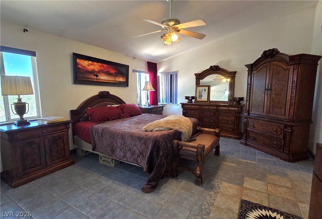 884 E Robindale Road, Las Vegas, NV 89123 A comfortable bedroom with elegant wood furnishings features cool tile flooring and a ceiling fan.