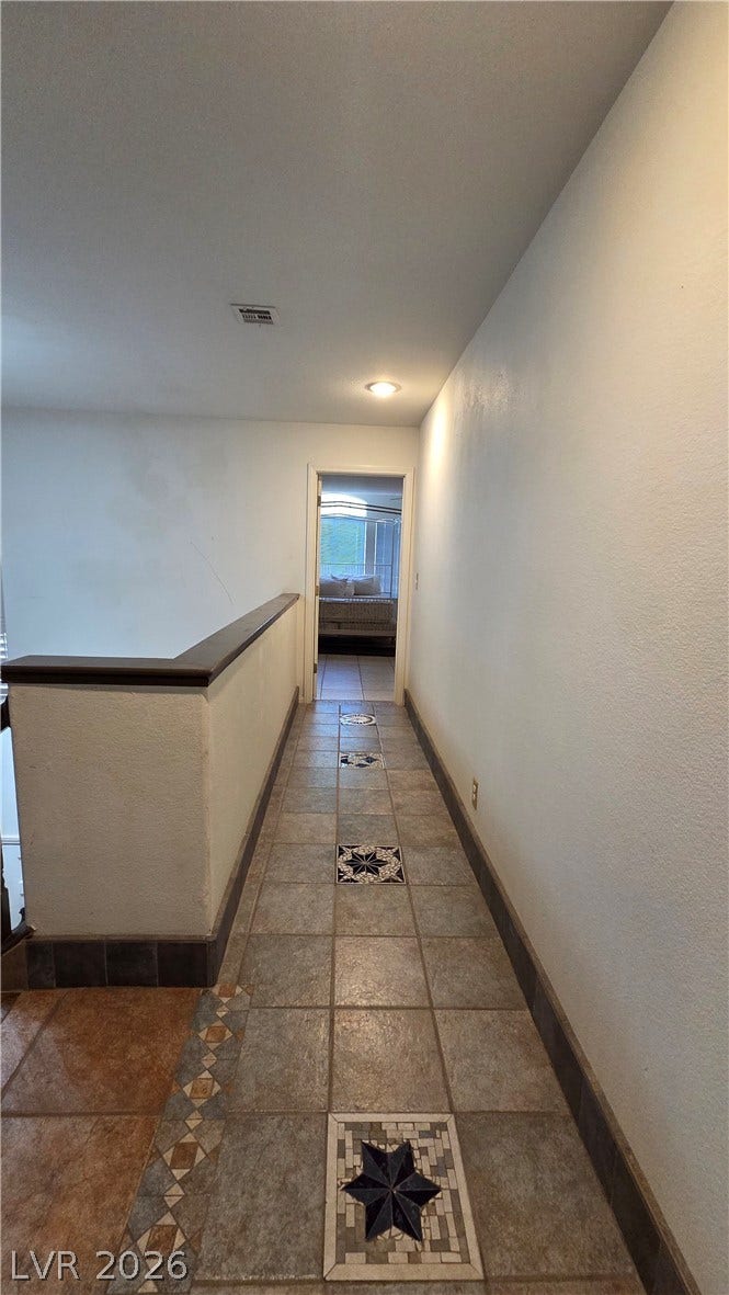884 E Robindale Road, Las Vegas, NV 89123 A well-lit hallway with unique patterned tile flooring leads to a private bedroom space.