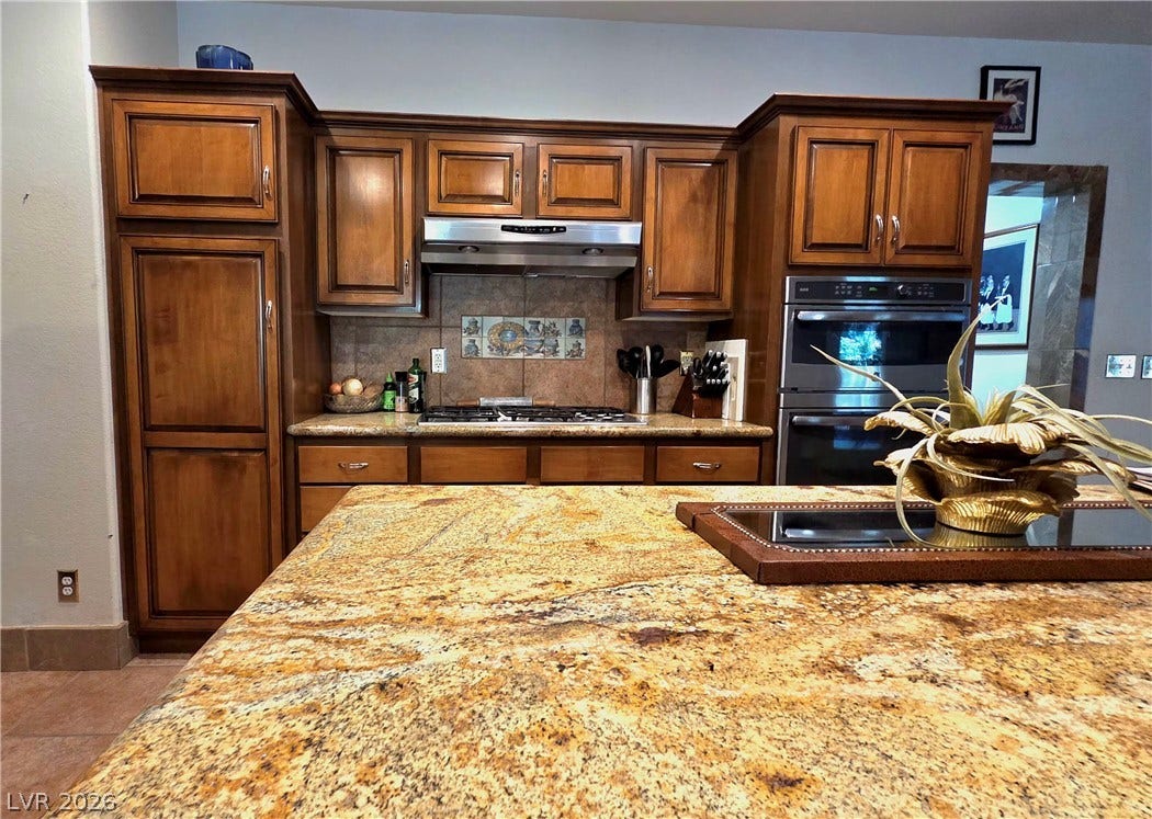 884 E Robindale Road, Las Vegas, NV 89123 Culinary delights await in this kitchen featuring abundant wood cabinetry and generous granite counter space.