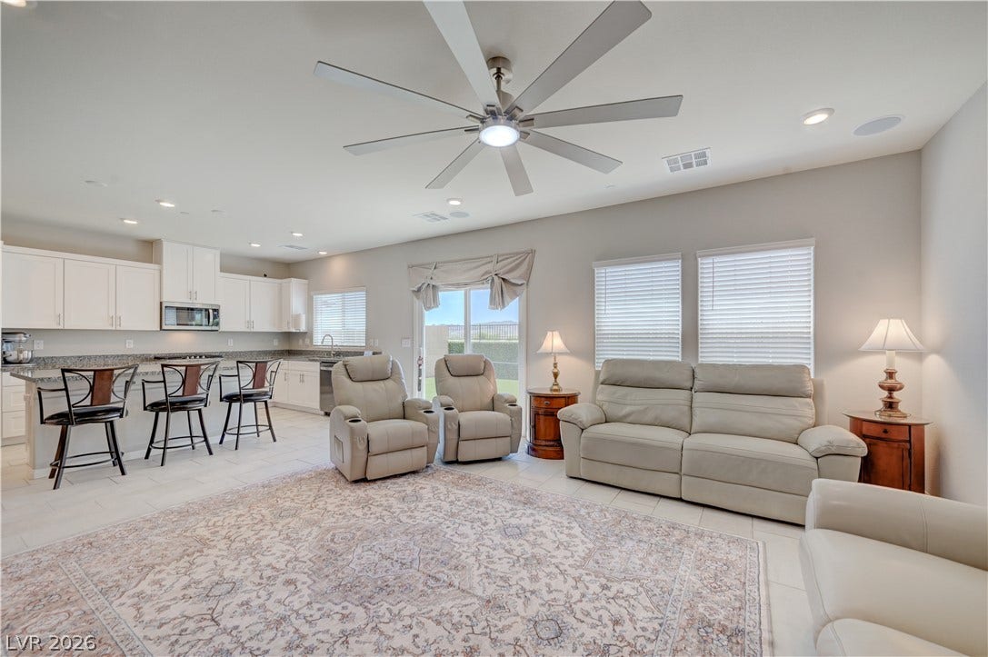 Natural light illuminates this spacious living area with outdoor access and contemporary tile flooring with oversized ceiling fan & light, ceramic tile floors & two tone paint and surround sound with speakers that flows seamlessly into the kitchen and dining area
