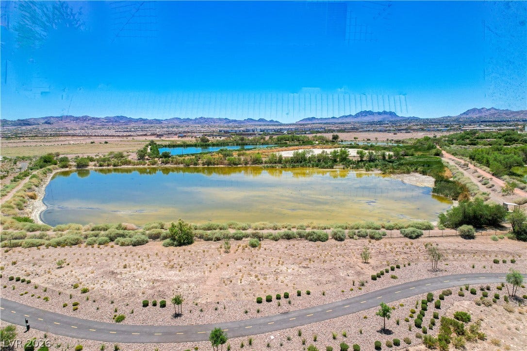 Vast desert landscape frames serene lakes and distant mountains under a boundless blue sky.