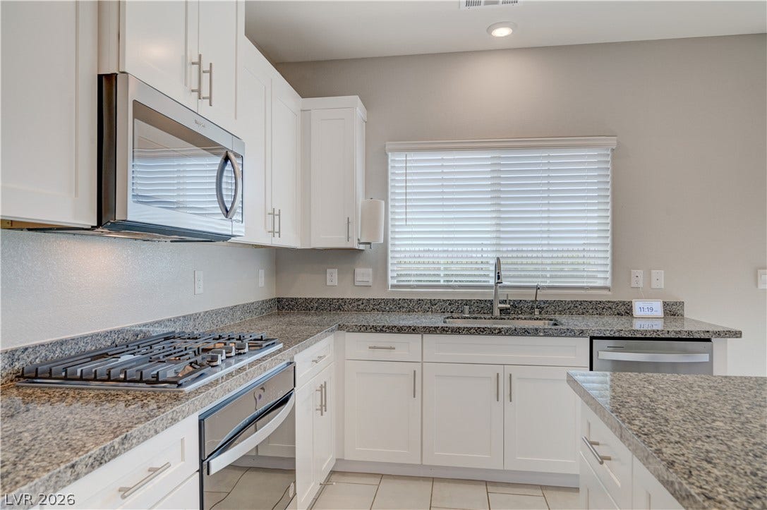 White cabinetry, granite counters, and stainless appliances define this contemporary kitchen's appeal.