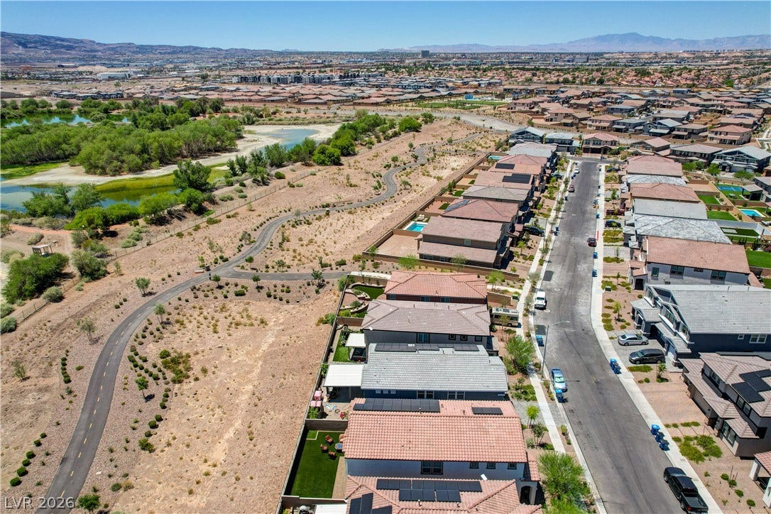 An aerial panorama showcases a desert community nestled beside a winding path and natural water features of the Henderson bird preserve.