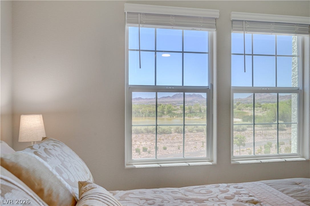 Natural light floods this bedroom with sweeping views of the surrounding landscape.