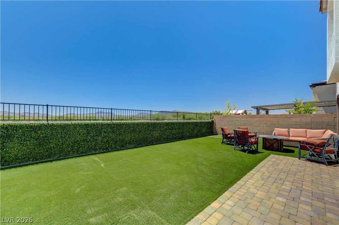 A spacious backyard retreat features artificial turf, a paver patio, and mountain views.
