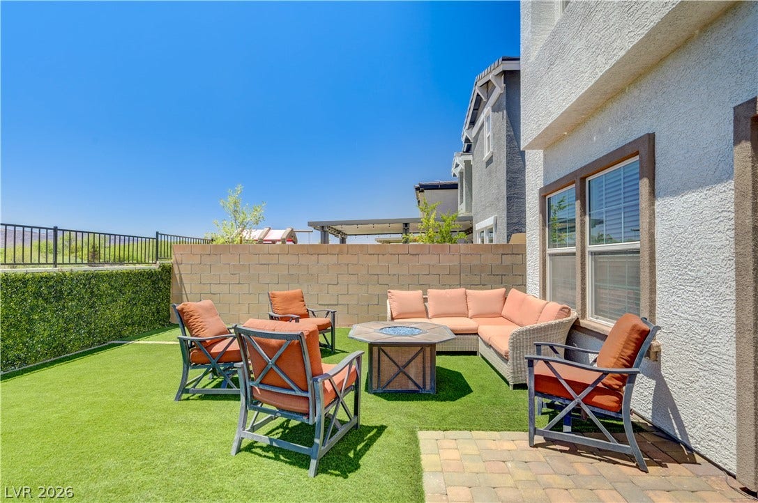 A well-appointed outdoor lounge area features an artificial turf lawn and a paver patio, perfect for relaxing.
