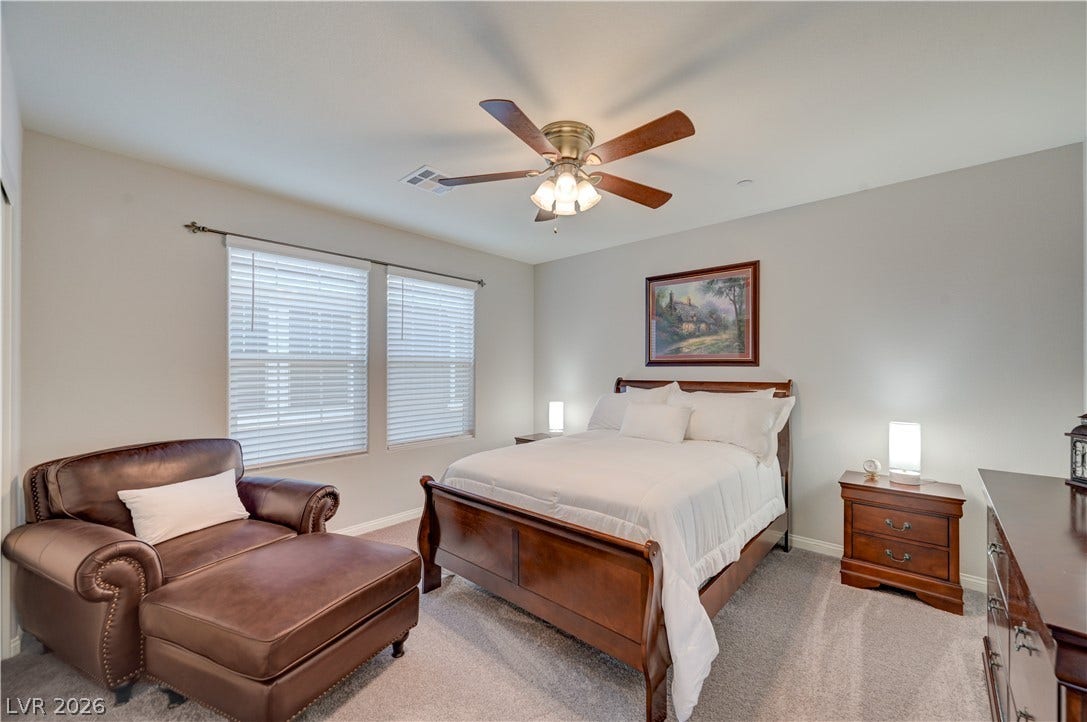 Relax in this tranquil 4th bedroom, featuring soft carpet, bright windows, and a warm ceiling fan.