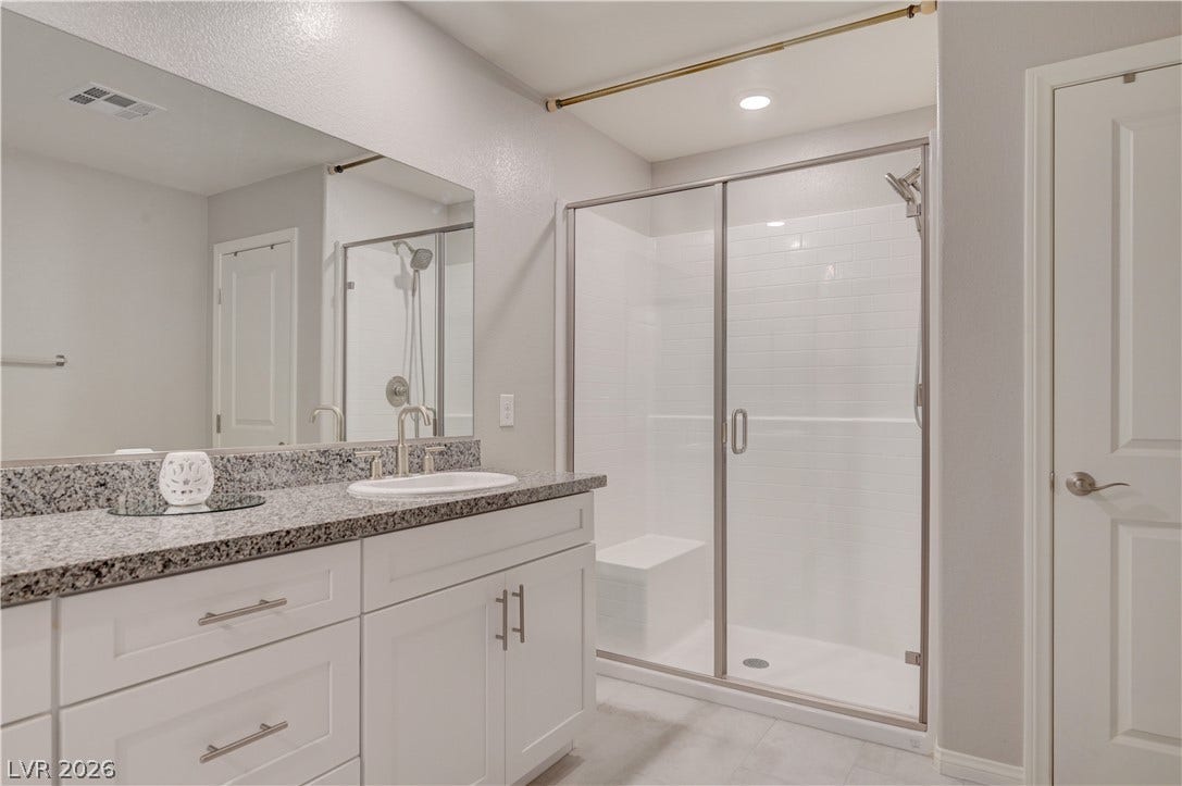 A well-lit bathroom showcases a spacious walk-in shower and an elegant vanity with ample counter space.
