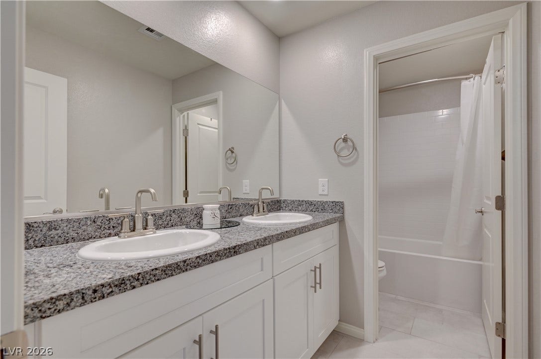 Double vanity with granite counters and expansive mirror for effortless morning routines.