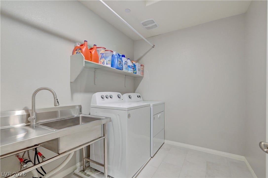 A dedicated upstairs laundry room equipped with a stainless steel utility sink and modern appliances.