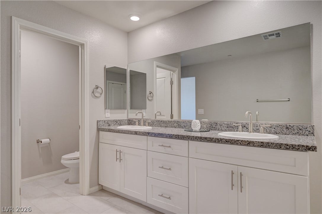 Dual vanities with granite counters provide ample space in this well-appointed bathroom.