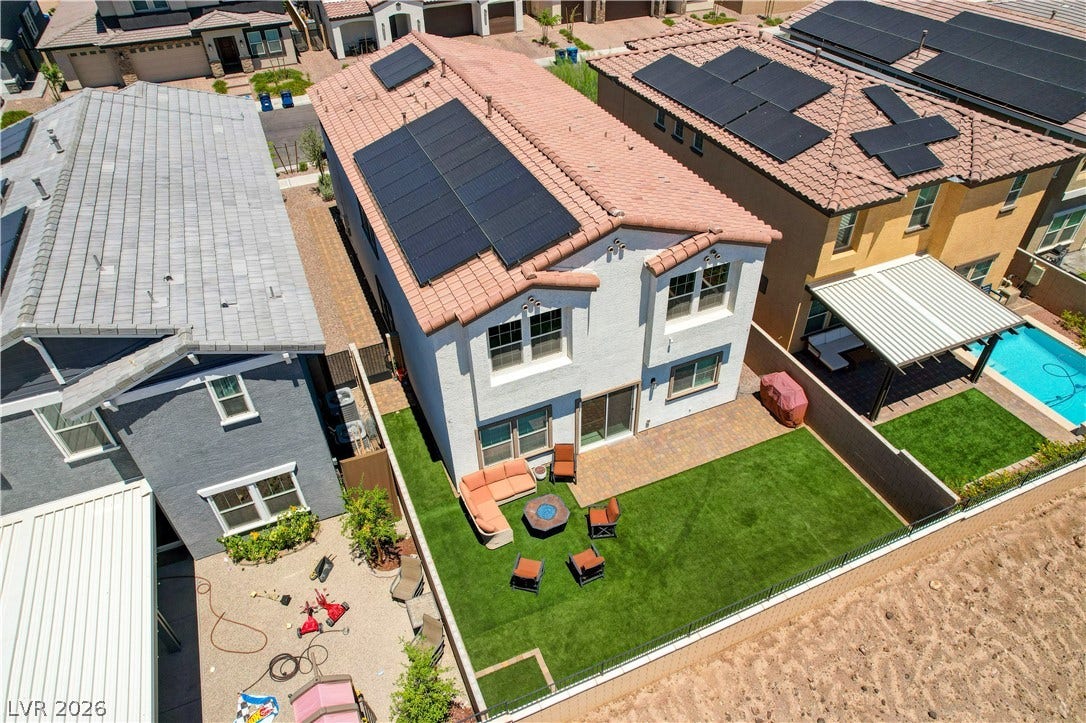 An aerial view captures the home's rear exterior, showcasing a well-manicured yard with pavers and a private pool.