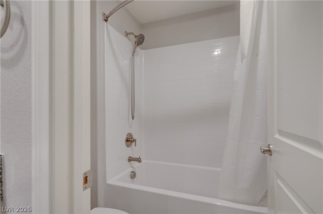 A pristine white tub and shower combination with sleek fixtures offers a relaxing bathing experience.
