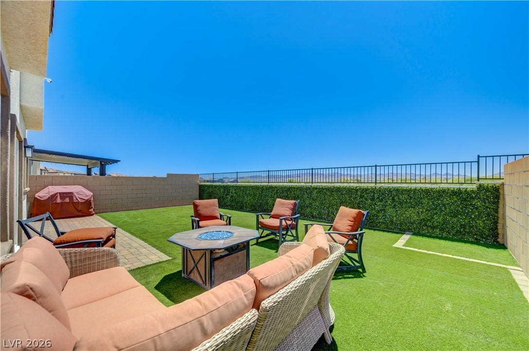 An inviting backyard oasis offers both relaxation and a sense of privacy with a fire pit and lush greenery.