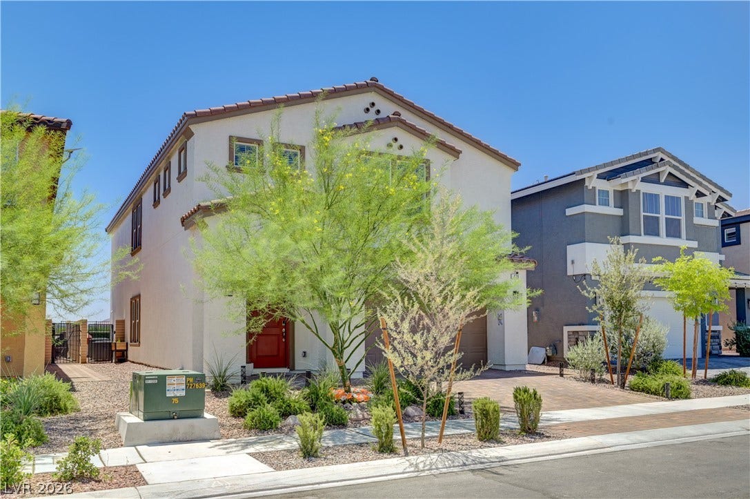 A terracotta-tiled roof crowns this stucco-sided residence, featuring a vibrant red front door and neatly landscaped yard.