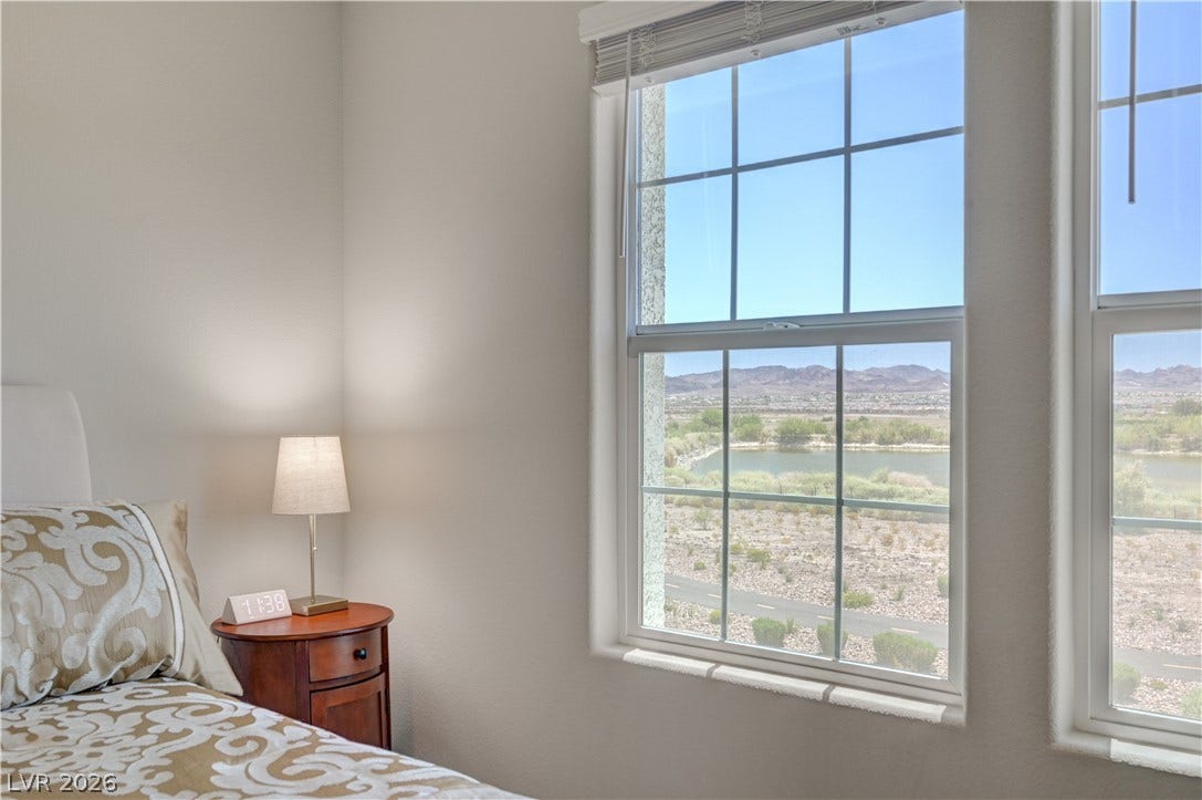 A well-lit 2nd bedroom offering picturesque views of a serene lake and distant mountains through a gridded window.