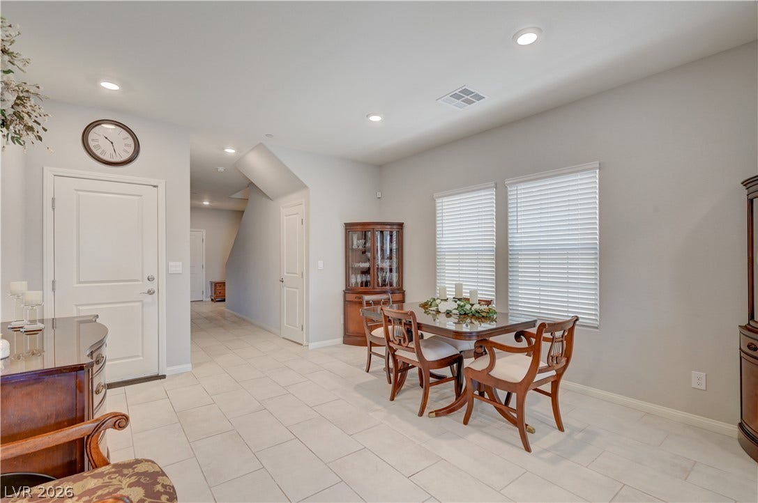 A well-lit formal dining area featuring tiled flooring and elegant recessed lighting.