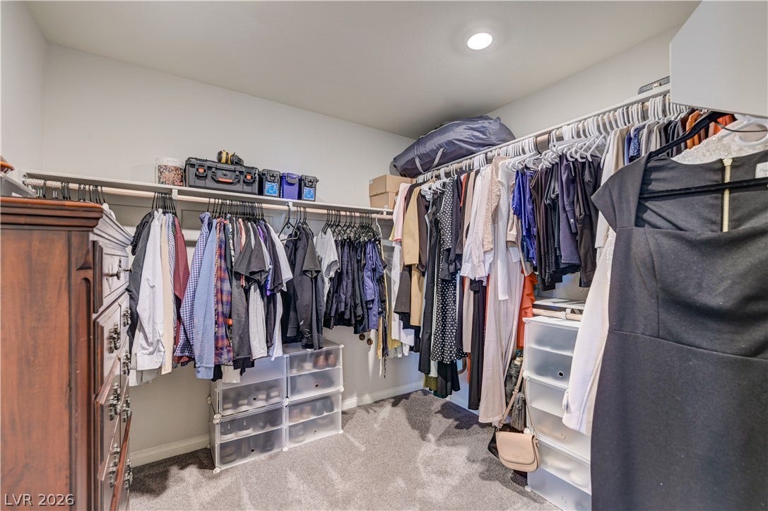 An organized primary bedroom walk-in closet with ample storage for clothing and accessories.