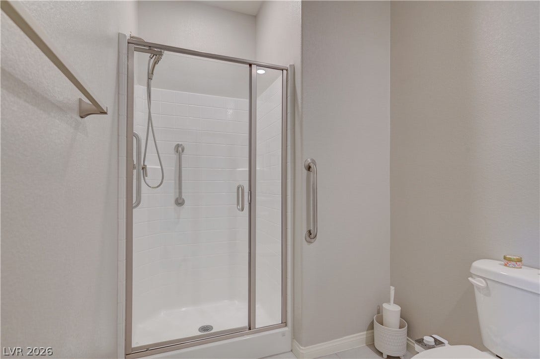 A well-appointed downstairs bathroom vanity features a sink with granite counters and ample cabinet storage, shower & tile floors.