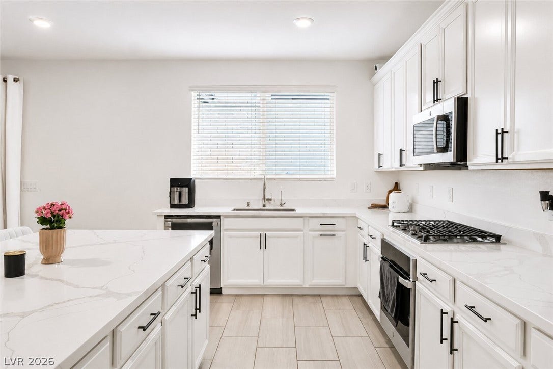 A well-lit culinary space featuring extensive countertop surfaces and modern cooking amenities.