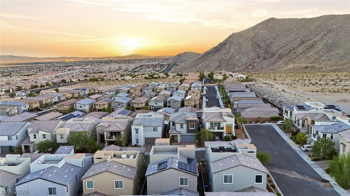 Sunset views frame the modern neighborhood nestled against the rugged desert hillside.