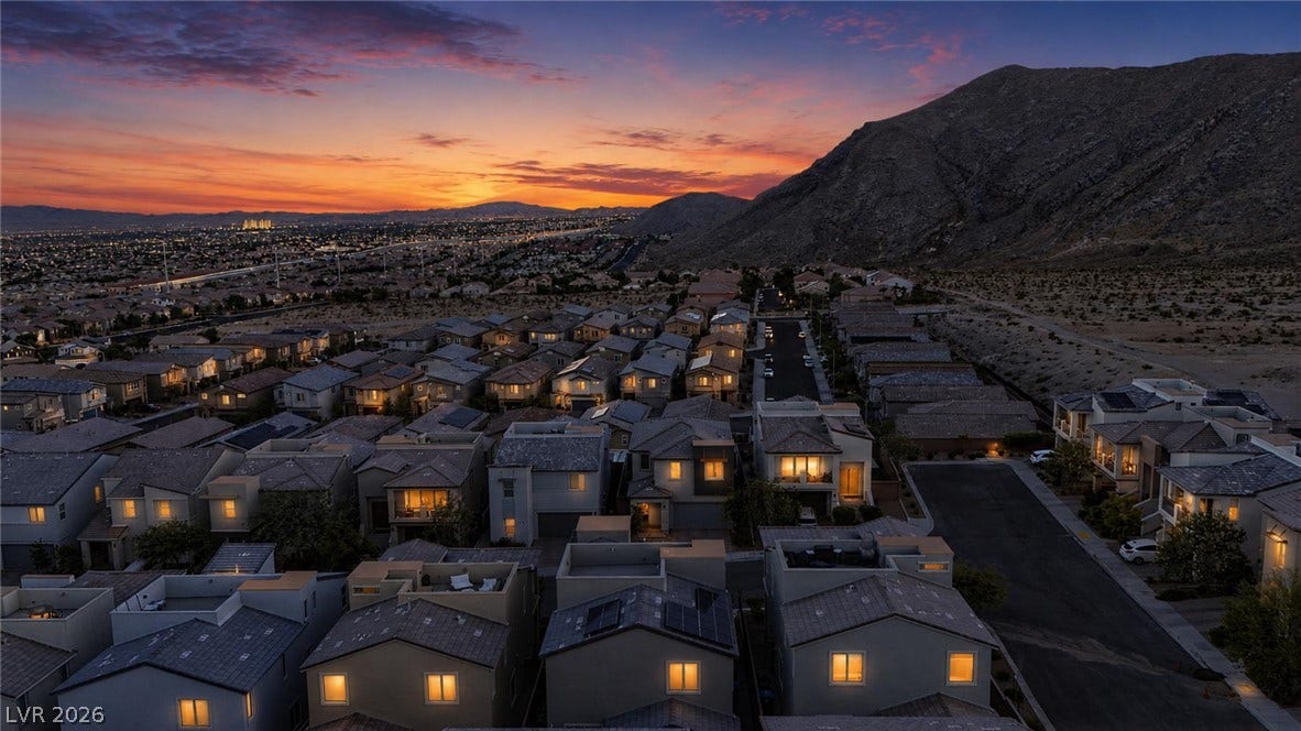 Dramatic sunset skies frame a peaceful hillside neighborhood overlooking sparkling city lights.