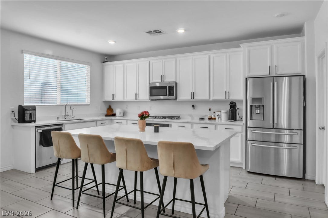 A well-lit kitchen with sleek white cabinetry, gleaming countertops, and a generous island for casual dining.