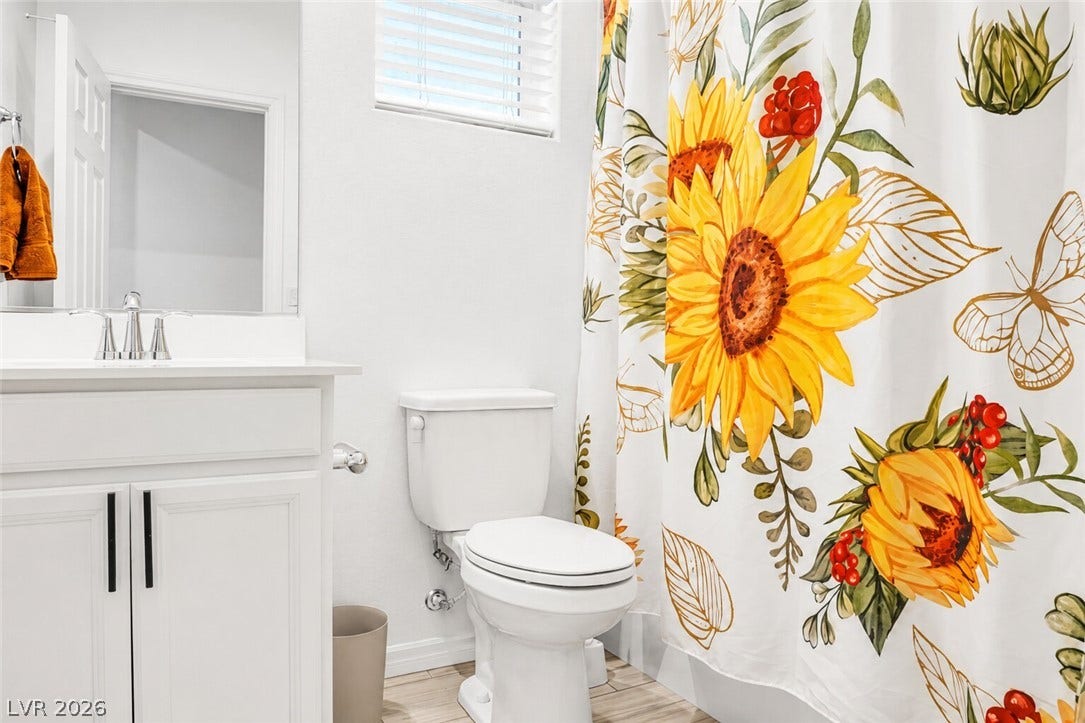 A pristine bathroom features a crisp white vanity and bright shower curtain with sunflower accents.