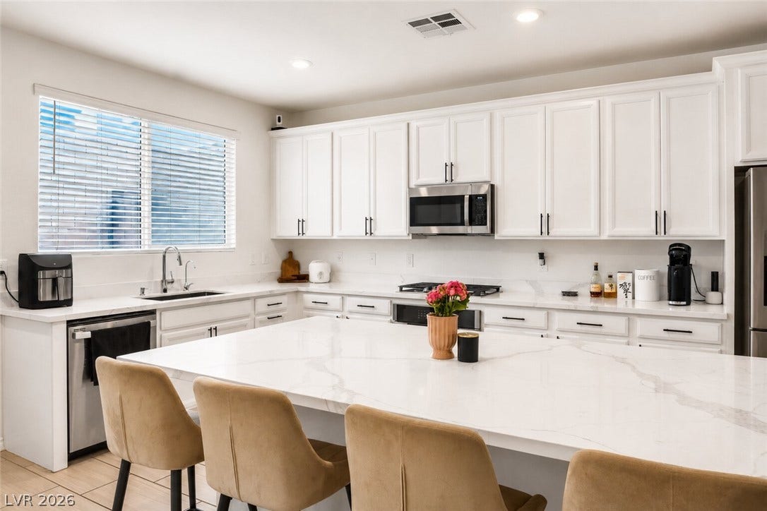 A well-lit kitchen with sleek white cabinetry, gleaming countertops, and an inviting island, perfect for entertaining.