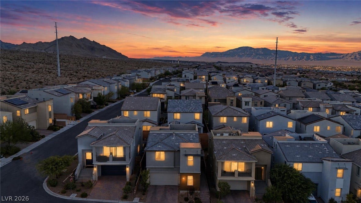 Dramatic mountain ranges frame a modern neighborhood setting during a vibrant desert sunset.