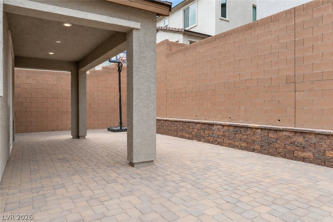 A shaded patio area, paved with interlocking stones, offers an inviting space for outdoor leisure.