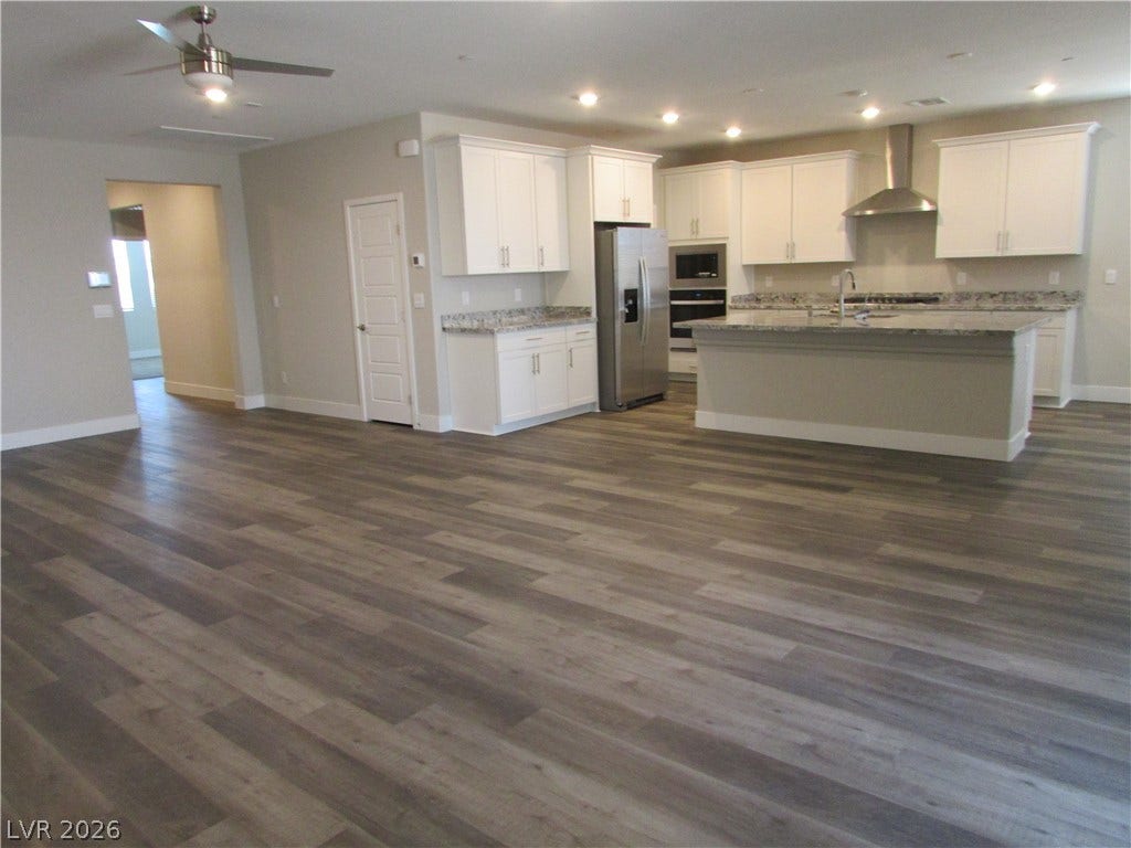 510 CHESTNUT FALCON AVE, Henderson, NV 89011 An open-concept living area boasts continuous plank flooring, leading to a modern kitchen with a large island.