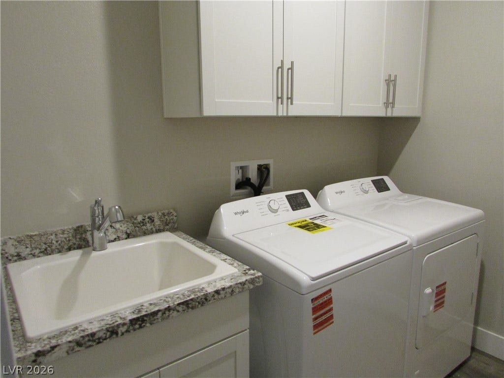 510 CHESTNUT FALCON AVE, Henderson, NV 89011 A well-appointed laundry room features a convenient utility sink, sleek granite countertops, and practical overhead cabinetry. Photo is Actual Home.