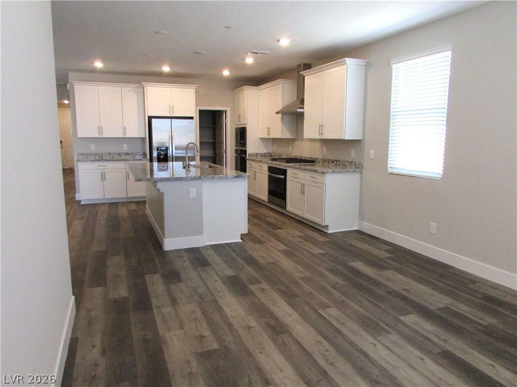 510 CHESTNUT FALCON AVE, Henderson, NV 89011 A well-appointed kitchen features a central island, modern appliances, and generous counter space, all complemented by durable plank flooring.