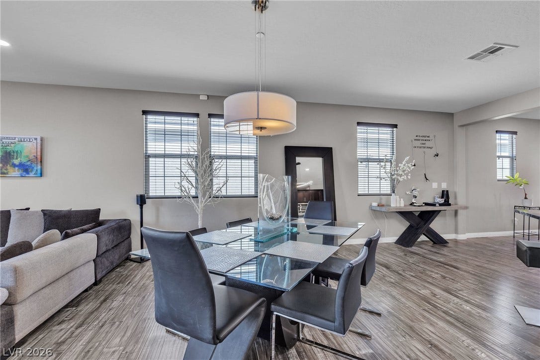 3106 Berceto Court, Henderson, NV 89044 A striking glass-top dining table anchors this open-concept living space, illuminated by an elegant overhead light fixture.