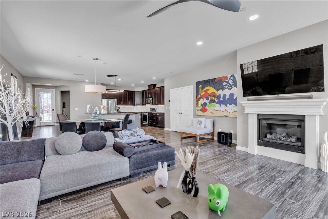 3106 Berceto Court, Henderson, NV 89044 An open-concept living area boasts a modern fireplace, high ceilings, and beautiful hardwood-style flooring.