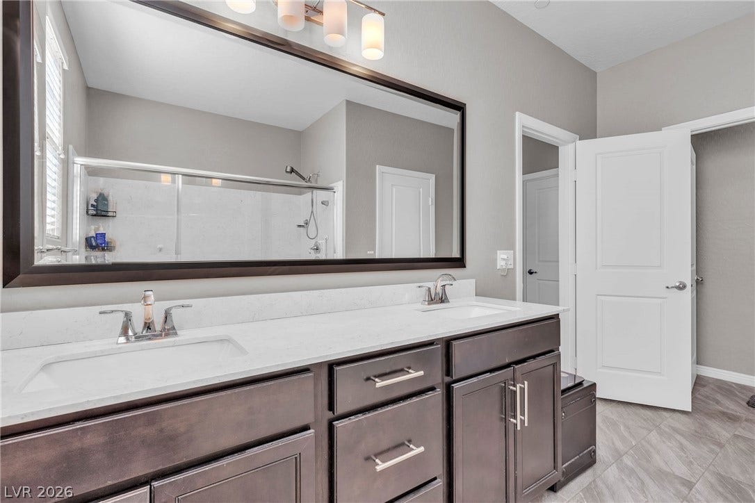 3106 Berceto Court, Henderson, NV 89044 A sleek vanity with dual sinks, an oversized mirror, and ample storage defines this well-appointed bath.