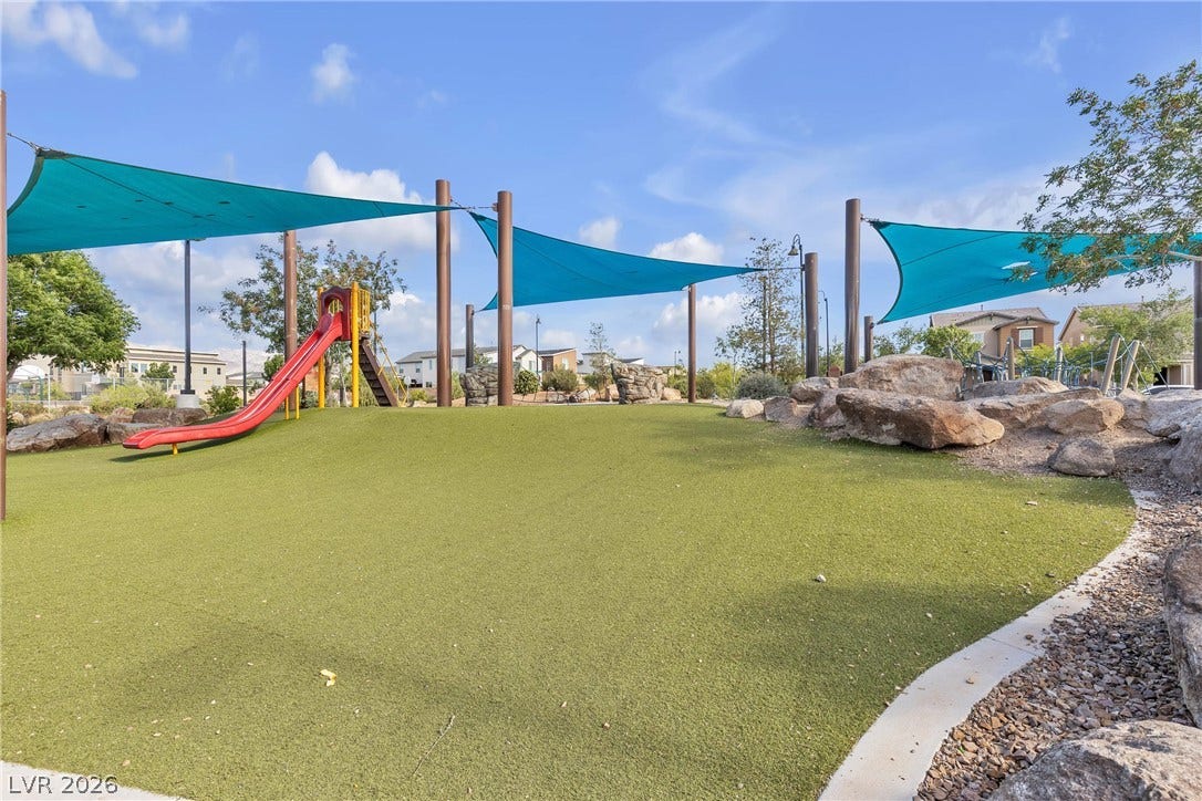 3106 Berceto Court, Henderson, NV 89044 A vibrant green playground area offers shaded recreation under bright blue canopies and a classic red slide.